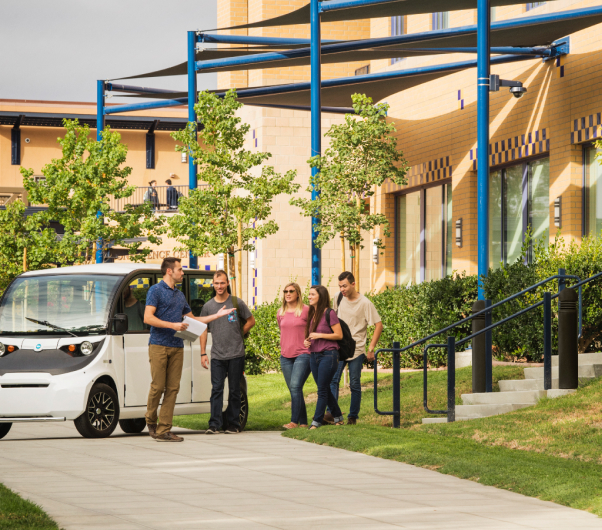 People on a tour standing next to an electric vehicle