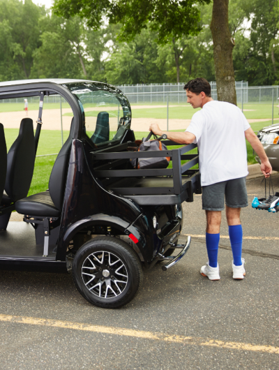 A man loading sports gear into the back of an electric vehicle
