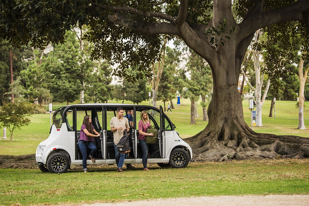 People exiting and electric shuttle vehicle in the park