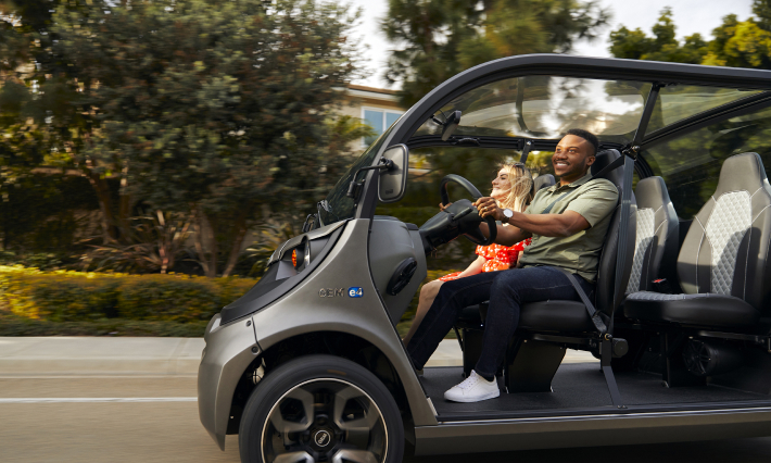 A man and a woman cruising through the neighborhood in an electric vehicle