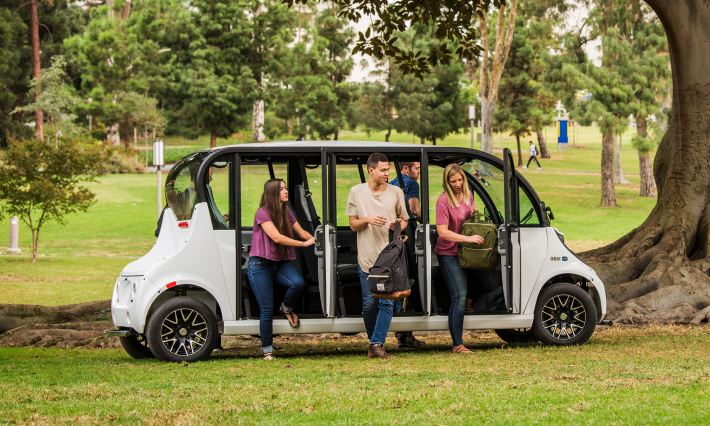 People exiting an electric shuttle vehicle in the park