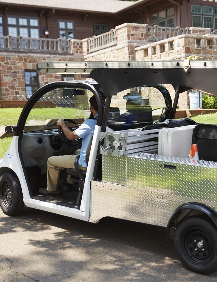 A man in a white safety utility vehicle parked outside of a building