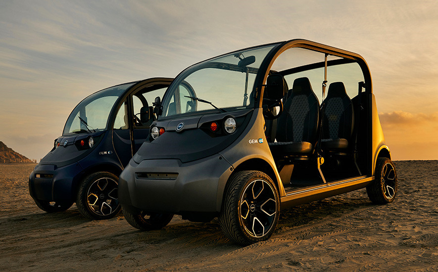 two side by side black electric vehicles in the sand at sunset