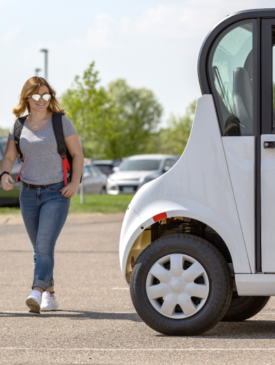 A woman in sunglasses walking up to an electric vehicle