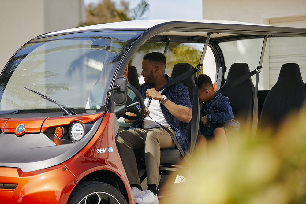 Family fastening seatbelts inside a red electric vehicle