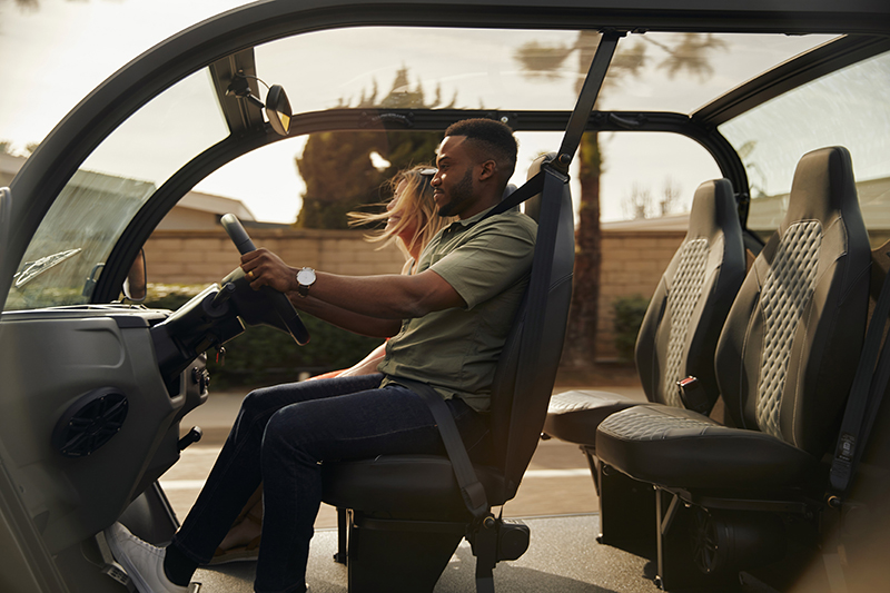 A man and a woman cruising through the neighborhood in an electric vehicle