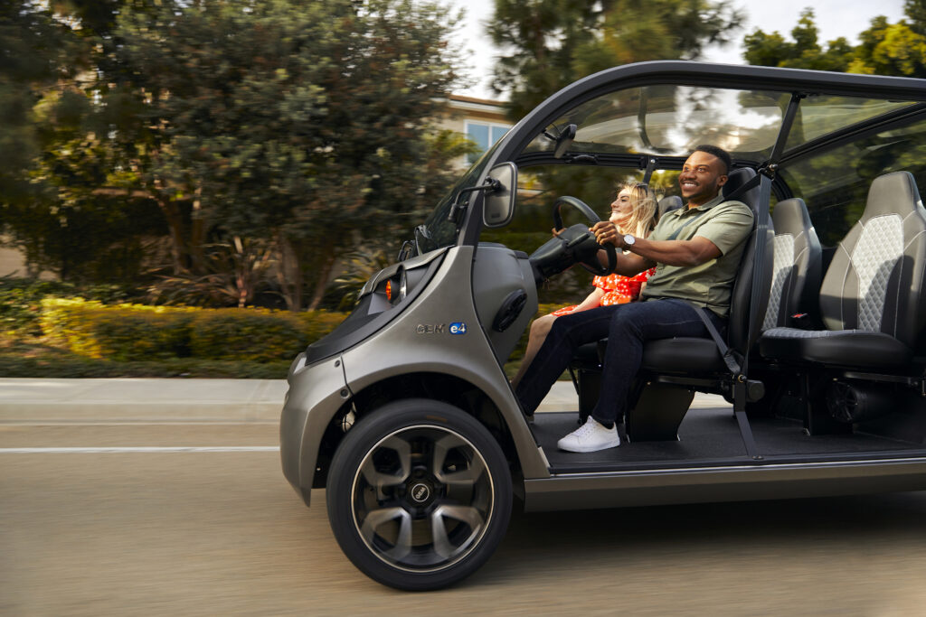 A man and a woman riding down the street in a black electric vehicle