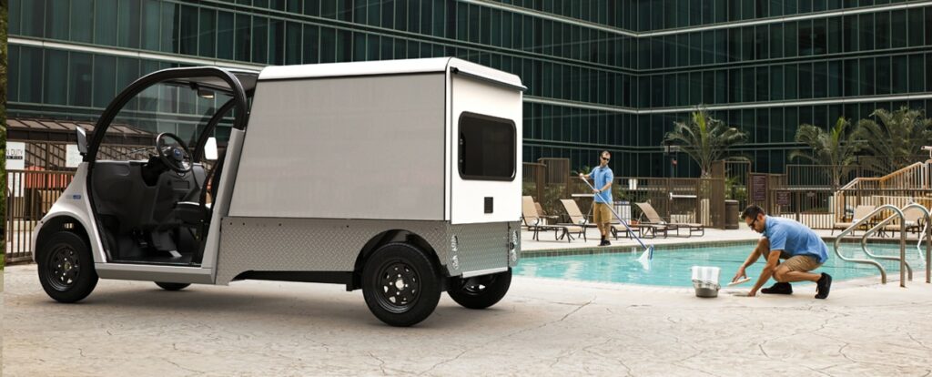 Poolside photo of a man doing maintenance next to a white electric vehicle