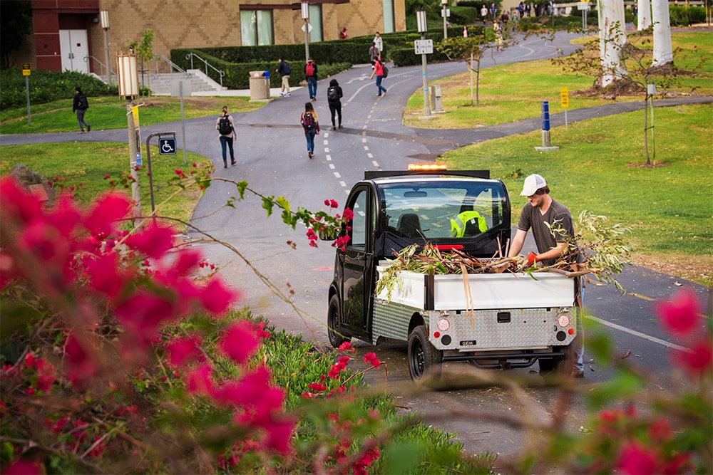 Man loading branches into the cab of an electric vehicle in the park