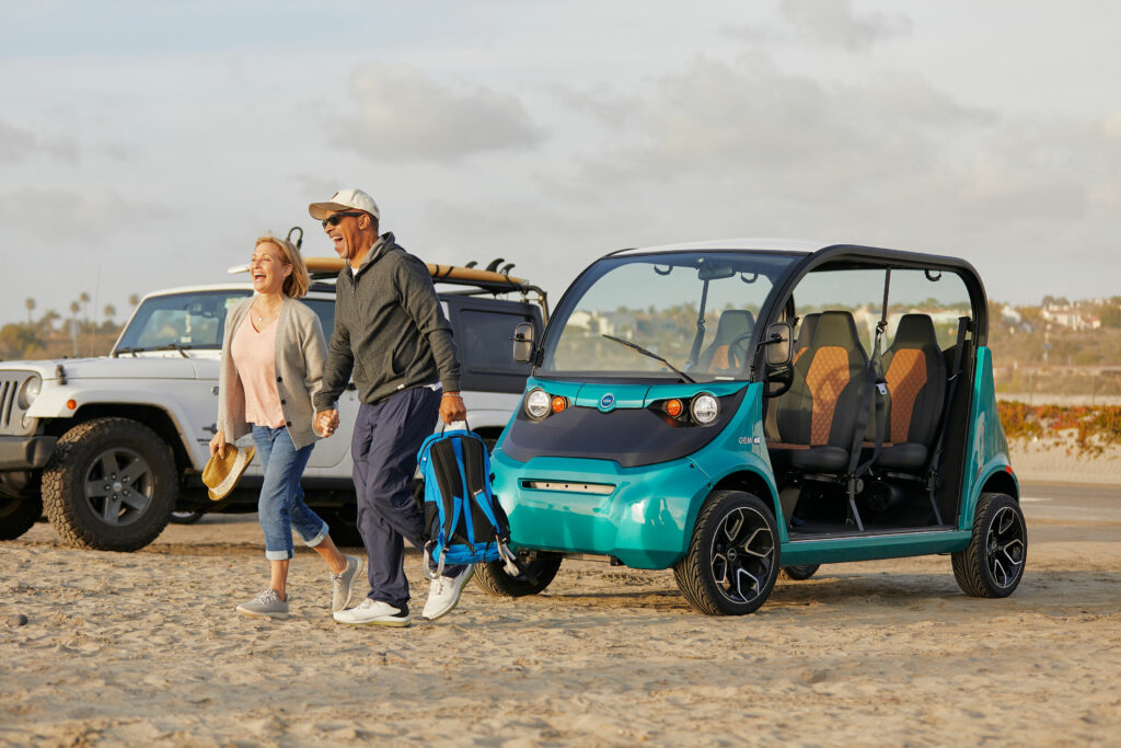 People carrying bags from their electric vehicle onto the beach