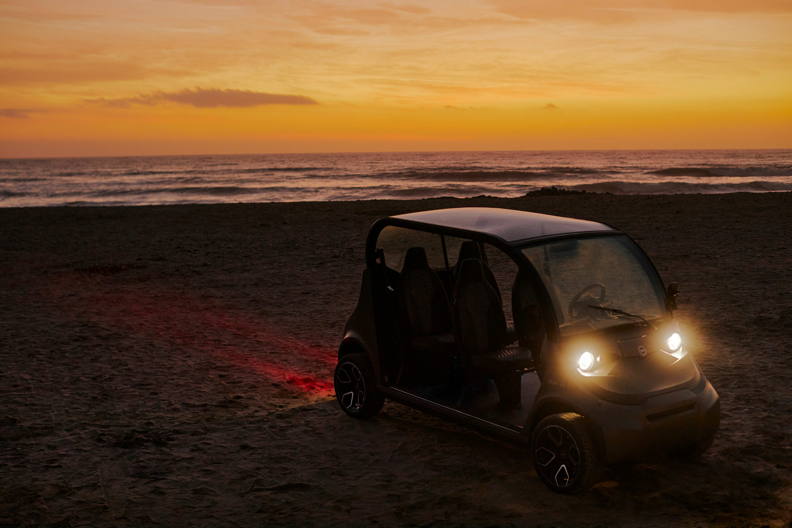 An electric vehicle in the sand at sunset
