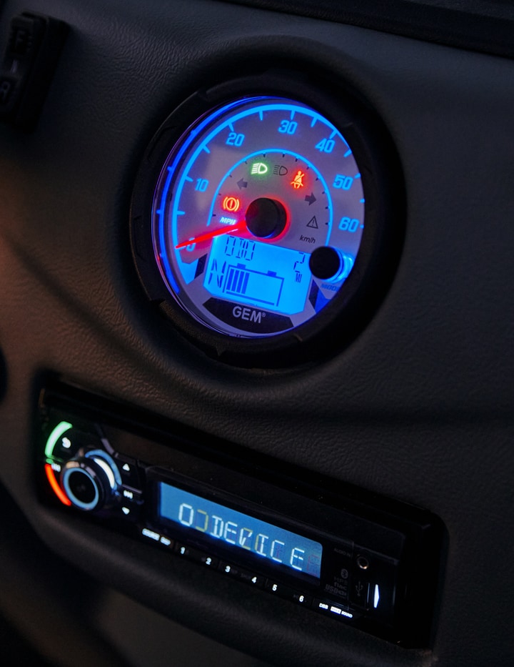 Close up of electric vehicle odometer and music deck lit up in blue