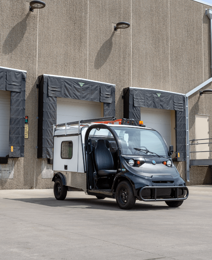 A black electric vehicle with a white enclosed trailerback