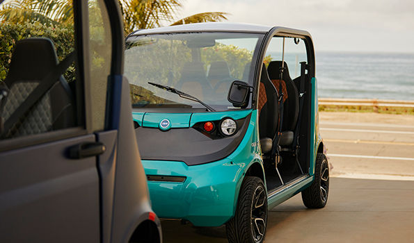 Close up of a teal electric vehicle parked on the street near the ocean